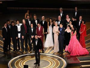 Produtor Jonathan Wang, ao centro, aceita o Oscar de melhor filme por &#039;Tudo Em Todo Lugar Ao Mesmo Tempo&#039;. Foto: Patrick T. Fallon / AFP