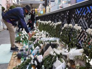  Uma pessoa deixa flores num espaço de luto temporário perto do local da trágica debandada de Halloween no distrito de Itaewon, em Seul. - -/YNA/dpa