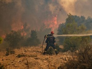 Um bombeiro apaga um incêndio em Kandyli, a oeste de Atenas, em 19 de julho de 2023